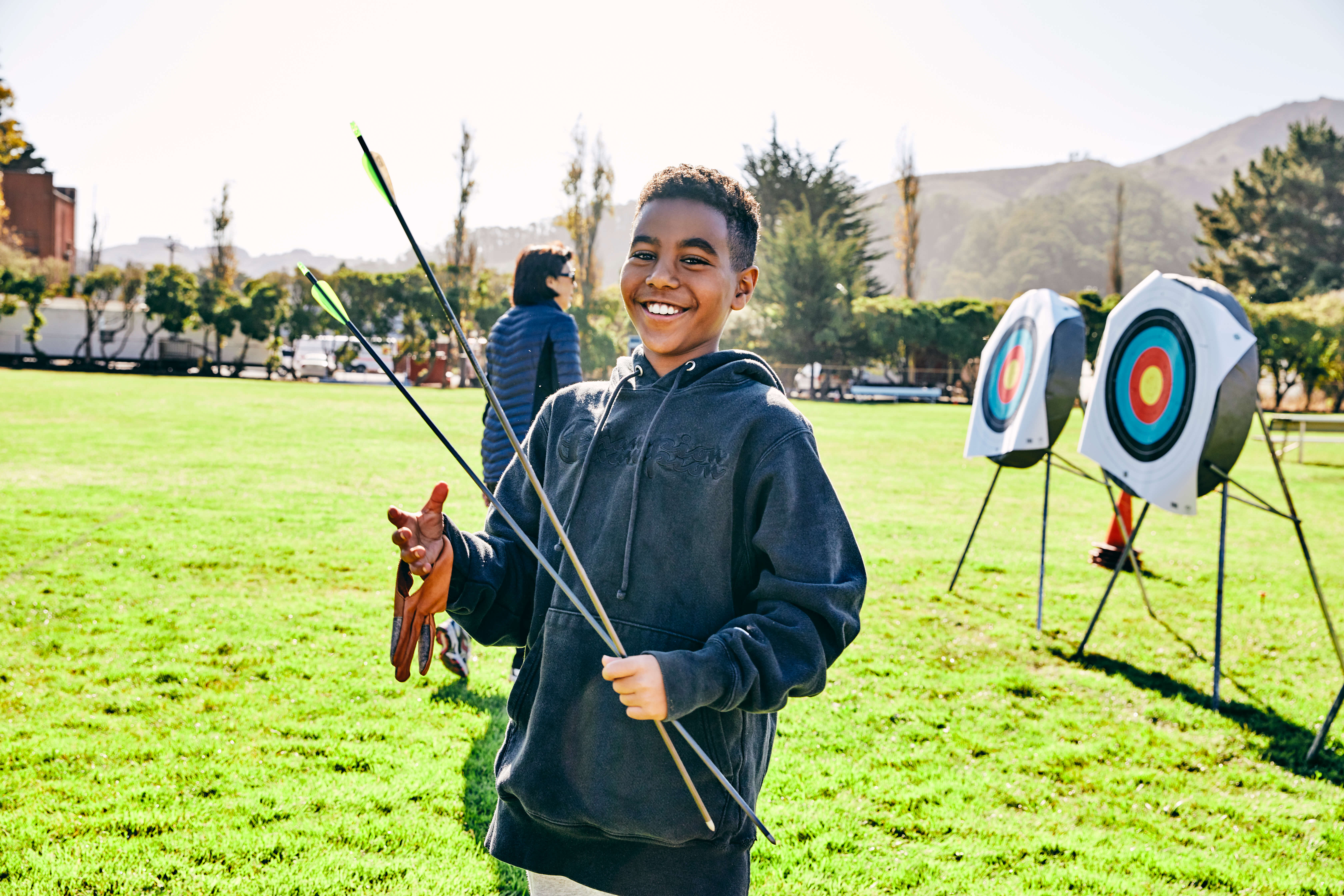 boy holding bow and arrows in front of archery targets